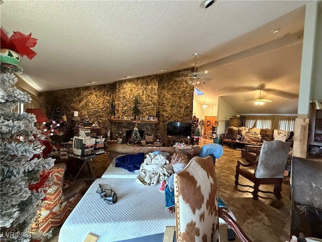 interior space featuring a stone fireplace, ceiling fan, and lofted ceiling