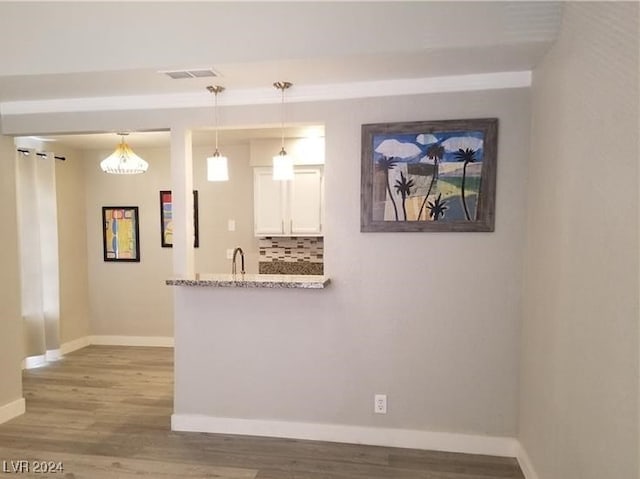 kitchen featuring decorative backsplash, white cabinetry, pendant lighting, and wood-type flooring