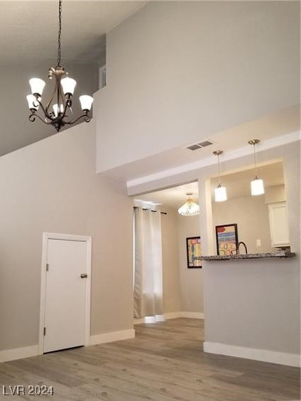 interior space with hardwood / wood-style floors, a high ceiling, and a notable chandelier