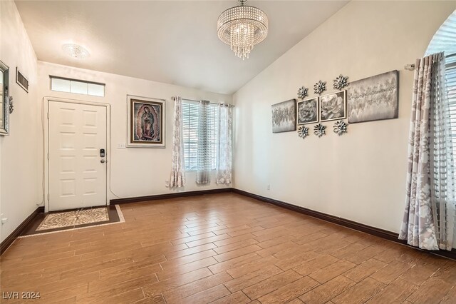 foyer with a chandelier, vaulted ceiling, and hardwood / wood-style flooring