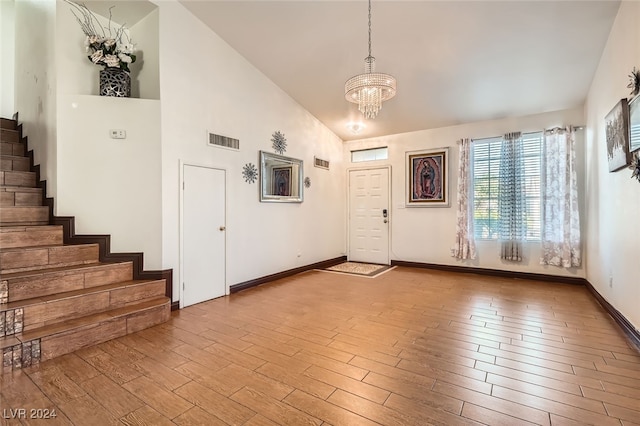 foyer entrance with light hardwood / wood-style flooring, high vaulted ceiling, and a notable chandelier