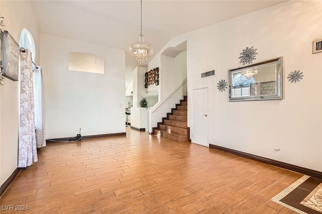 spare room with light wood-type flooring, high vaulted ceiling, and a chandelier