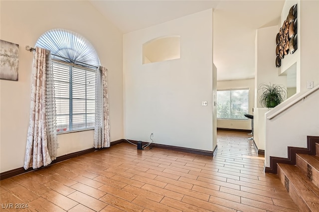 spare room with high vaulted ceiling and light hardwood / wood-style flooring