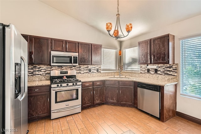 kitchen featuring pendant lighting, sink, vaulted ceiling, appliances with stainless steel finishes, and light hardwood / wood-style floors