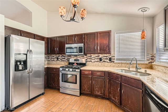 kitchen with sink, stainless steel appliances, an inviting chandelier, vaulted ceiling, and decorative light fixtures