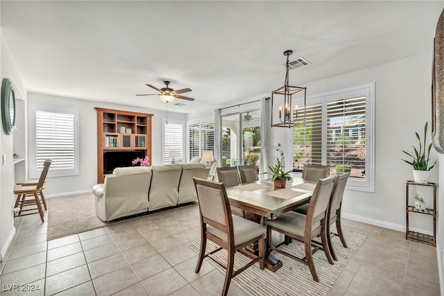 tiled dining area featuring ceiling fan with notable chandelier and a healthy amount of sunlight