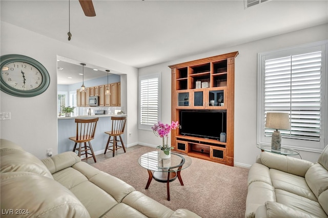 living room with a wealth of natural light, ceiling fan, and light carpet