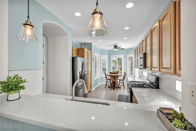 kitchen with ceiling fan, sink, tasteful backsplash, light stone counters, and appliances with stainless steel finishes