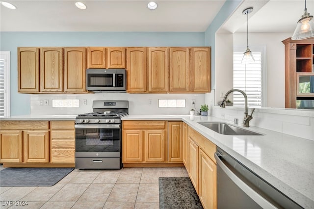 kitchen featuring hanging light fixtures, stainless steel appliances, light brown cabinets, and sink