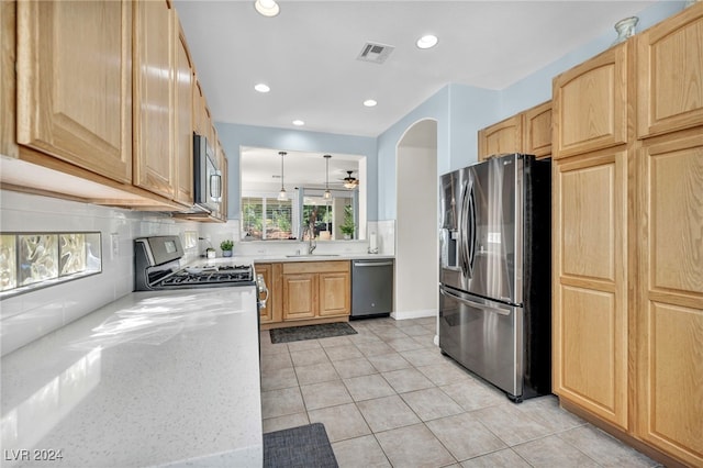 kitchen with light stone countertops, sink, stainless steel appliances, pendant lighting, and light tile patterned floors