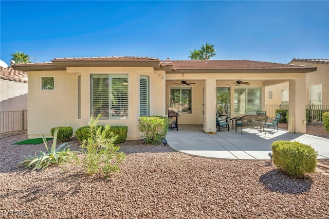 rear view of property featuring ceiling fan and a patio area