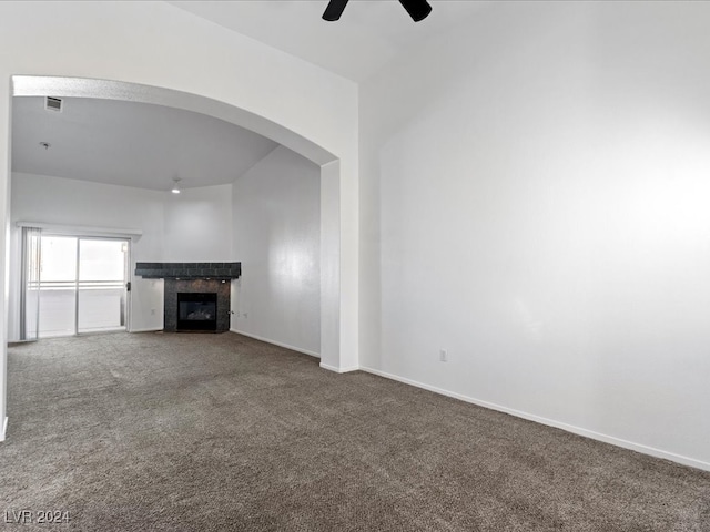 unfurnished living room featuring a tile fireplace, carpet, and ceiling fan