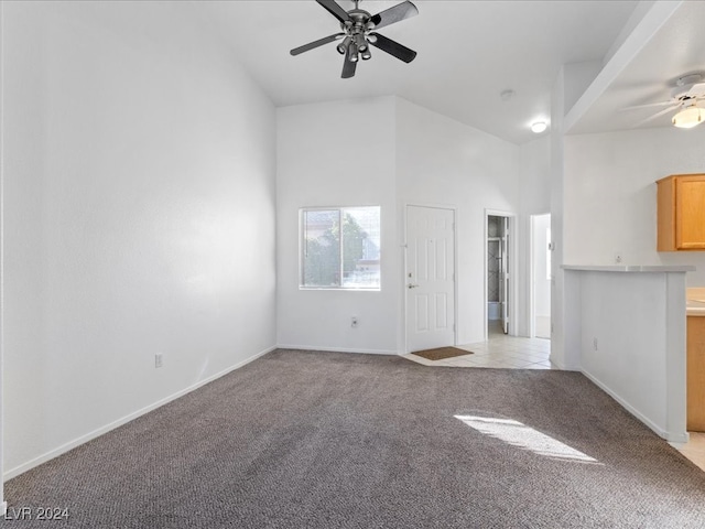 unfurnished living room featuring light carpet, a towering ceiling, and ceiling fan