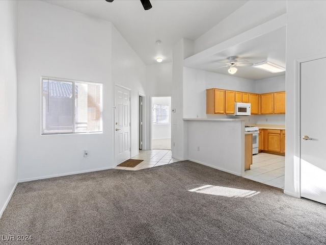 kitchen featuring ceiling fan, high vaulted ceiling, kitchen peninsula, white appliances, and light carpet