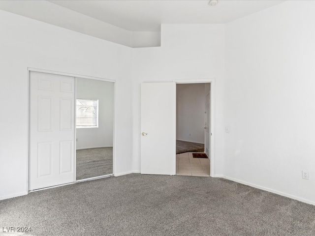 unfurnished bedroom with light colored carpet and a closet