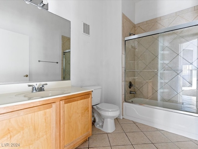 full bathroom featuring toilet, vanity, tile patterned floors, and bath / shower combo with glass door