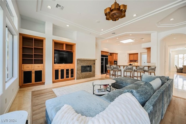 living room featuring a notable chandelier, built in shelves, and a high end fireplace