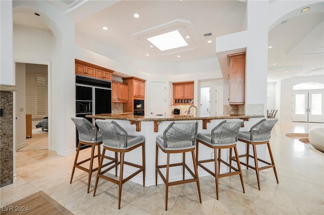 kitchen with sink, a breakfast bar area, light stone counters, tasteful backsplash, and kitchen peninsula