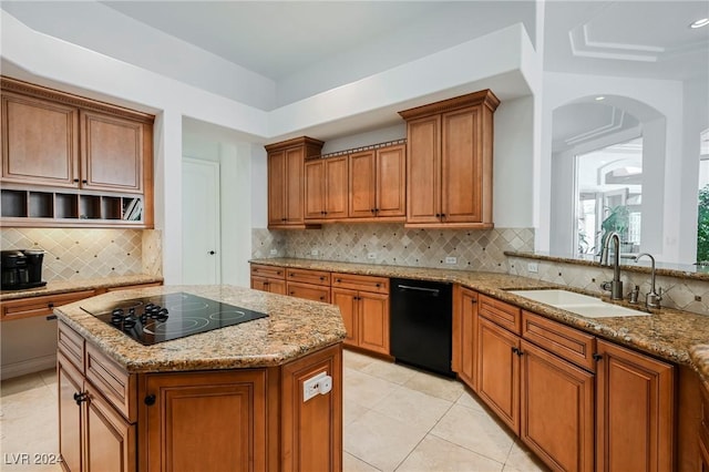 kitchen with a kitchen island, sink, backsplash, light stone counters, and black appliances