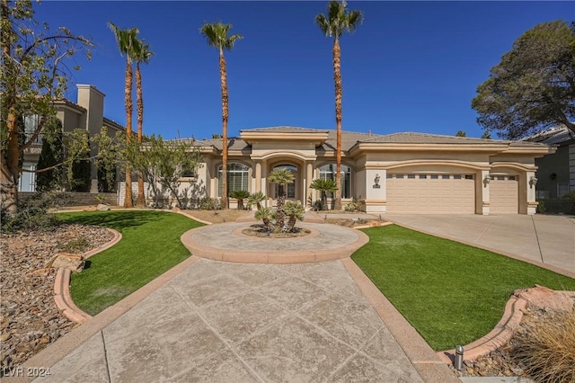 mediterranean / spanish house featuring a garage and a front lawn