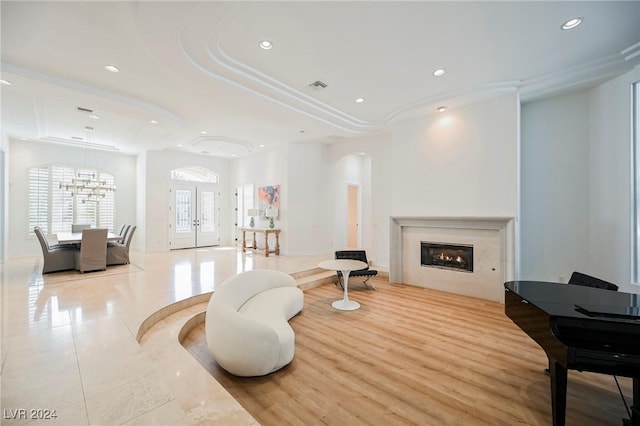 living room with french doors, a tray ceiling, and an inviting chandelier