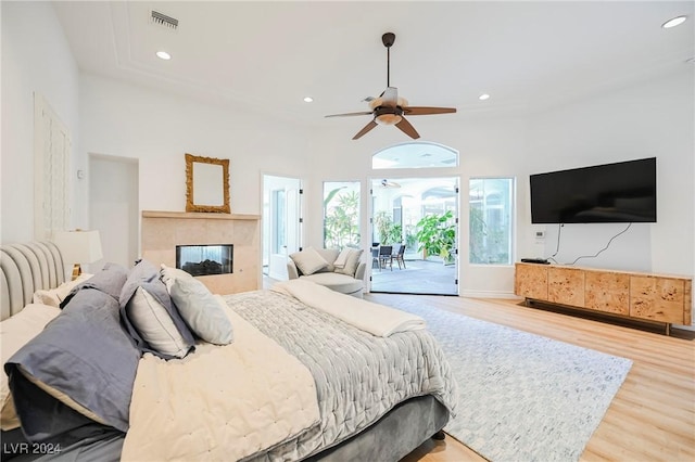 bedroom featuring ceiling fan, a fireplace, light hardwood / wood-style flooring, and access to outside