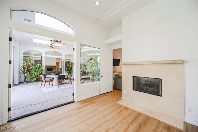 doorway featuring ceiling fan, a tiled fireplace, and light hardwood / wood-style flooring