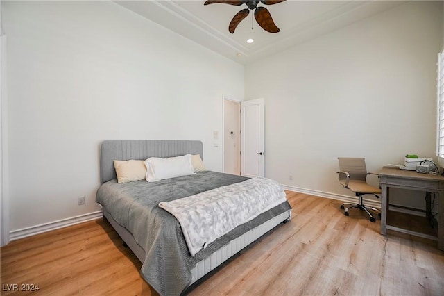 bedroom featuring ceiling fan, light hardwood / wood-style floors, and a towering ceiling