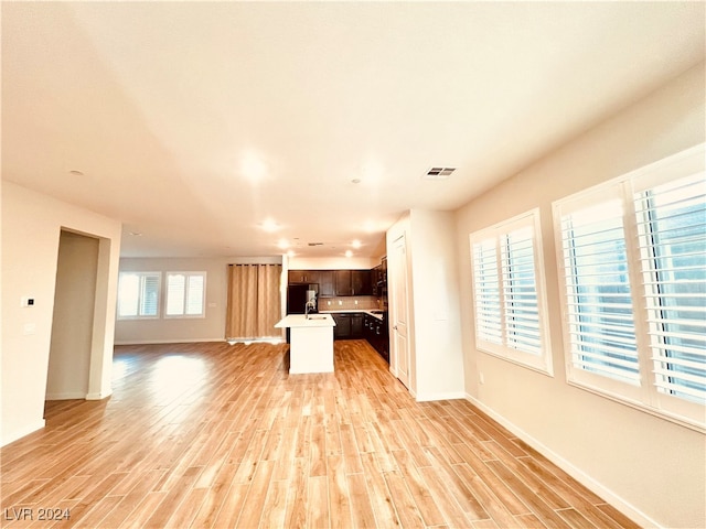 kitchen with refrigerator, dark brown cabinetry, light hardwood / wood-style flooring, and a kitchen island