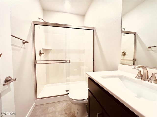 bathroom with tile patterned flooring, vanity, a shower with shower door, and toilet