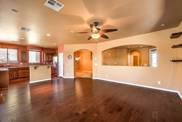 unfurnished living room featuring a textured ceiling, ceiling fan, dark hardwood / wood-style flooring, and sink