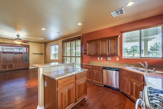 kitchen with stainless steel dishwasher, a healthy amount of sunlight, dark wood-type flooring, sink, and range