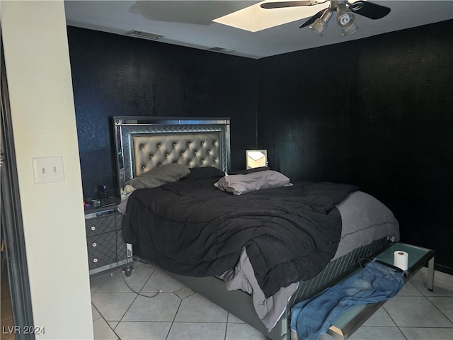 tiled bedroom featuring a skylight and ceiling fan