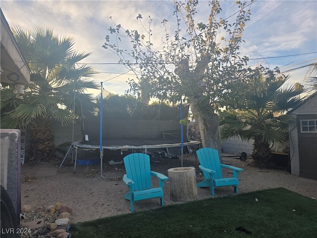 yard at dusk featuring a trampoline