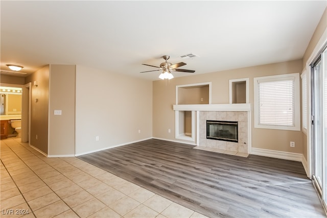 unfurnished living room featuring light hardwood / wood-style floors, ceiling fan, and a tiled fireplace