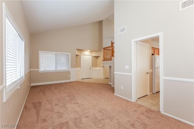 unfurnished living room featuring light colored carpet and high vaulted ceiling