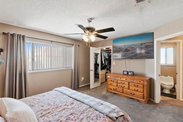 bedroom with dark carpet, ensuite bath, ceiling fan, a spacious closet, and a closet