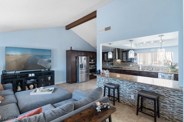 living room with vaulted ceiling with beams, light tile patterned flooring, and a textured ceiling