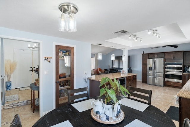 dining room with a tray ceiling, ceiling fan, and light tile patterned floors