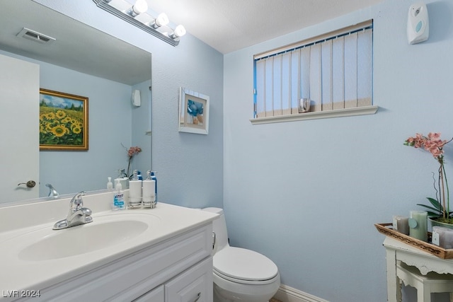 bathroom featuring vanity, a textured ceiling, and toilet