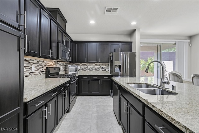 kitchen with light stone countertops, sink, decorative backsplash, light tile patterned floors, and appliances with stainless steel finishes