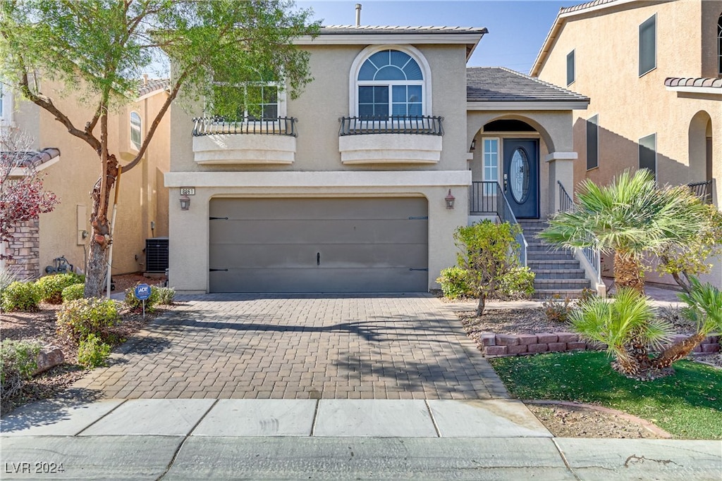 mediterranean / spanish-style house with central AC unit and a garage