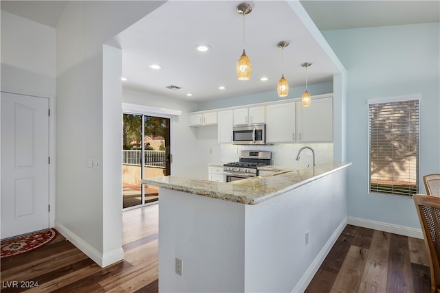 kitchen featuring hanging light fixtures, white cabinetry, dark hardwood / wood-style flooring, kitchen peninsula, and stainless steel appliances