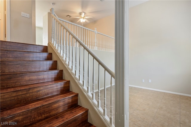 stairway featuring ceiling fan