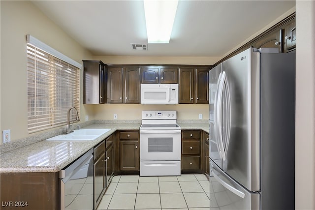 kitchen with light stone countertops, sink, stainless steel appliances, and dark brown cabinets