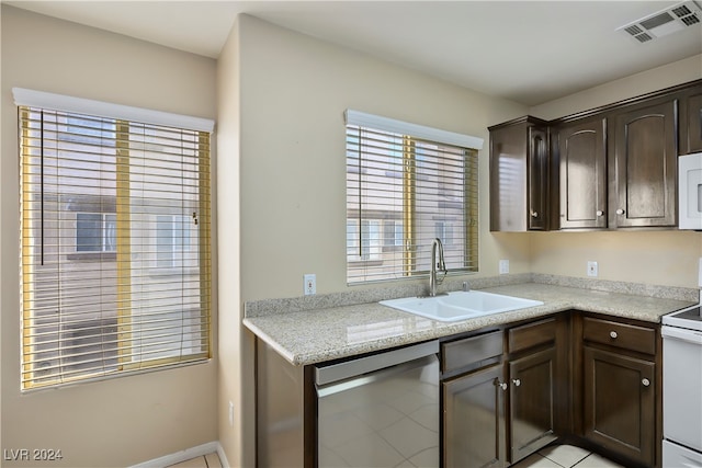 kitchen featuring light stone counters, dark brown cabinets, white appliances, sink, and light tile patterned floors