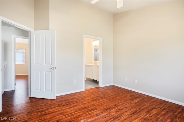 unfurnished bedroom featuring connected bathroom, ceiling fan, and dark wood-type flooring