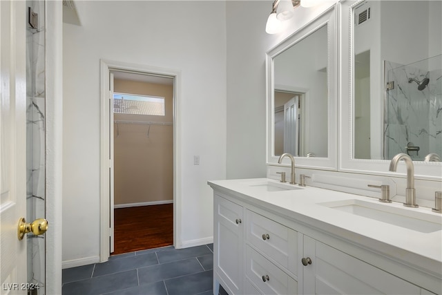 bathroom with tile patterned flooring, vanity, and tiled shower