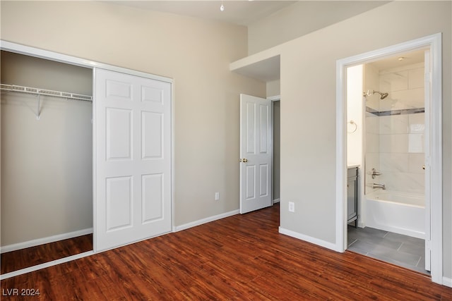 unfurnished bedroom with ensuite bathroom, a closet, and dark wood-type flooring