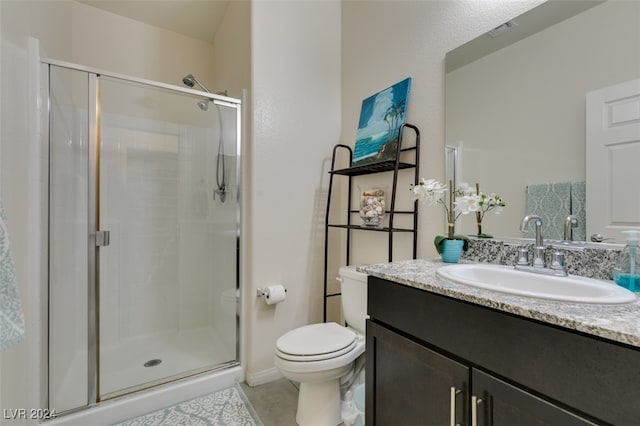 bathroom featuring tile patterned flooring, vanity, toilet, and a shower with shower door